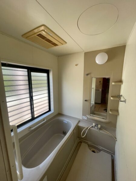 「兵庫県河辺郡の浴室リフォーム前の既存ユニットバスの様子。樹脂パネルの壁と既存浴槽が写っている解体前の状態」